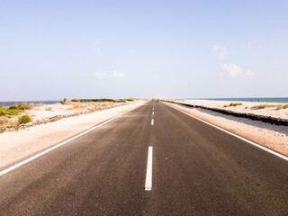 The asphalt road through sandy beaches leading to the island of Dhanushkodi near the town of Rameswaram in Tamil Nadu, India.