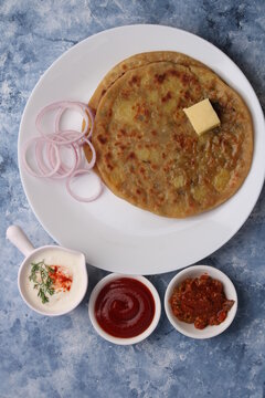 Traditional Indian food Aloo paratha or potato stuffed flat bread. served with pickle  tomato ketchup and curd, butter, onion.