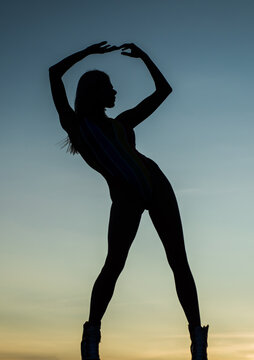 Woman ballet dancer shadow figure silhouetted on evening sky, silhouette