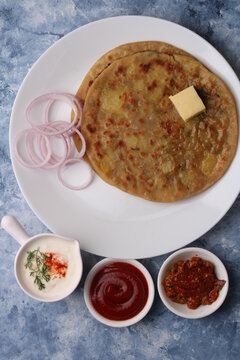 Traditional Indian food Aloo paratha or potato stuffed flat bread. served with pickle  tomato ketchup and curd, butter, onion.