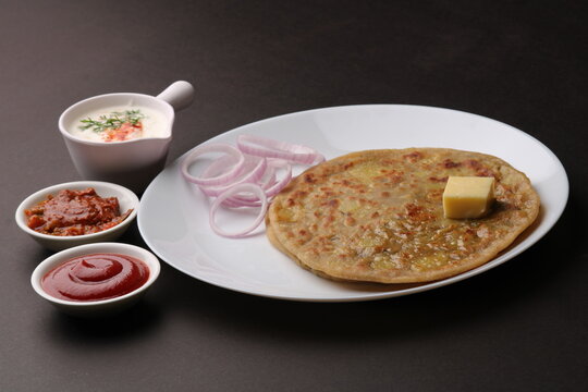 Traditional Indian food Aloo paratha or potato stuffed flat bread. served with pickle  tomato ketchup and curd, butter, onion.