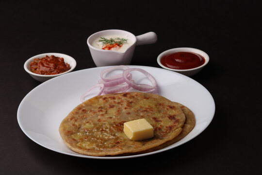 Traditional Indian food Aloo paratha or potato stuffed flat bread. served with pickle  tomato ketchup and curd, butter, onion.
