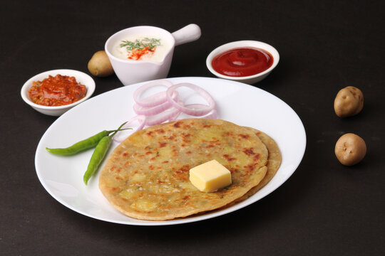 Traditional Indian food Aloo paratha or potato stuffed flat bread. served with pickle  tomato ketchup and curd, butter, onion, chili.