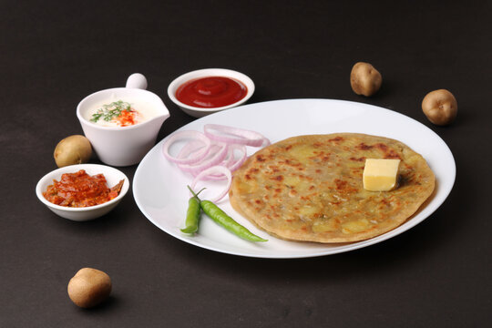 Traditional Indian food Aloo paratha or potato stuffed flat bread. served with pickle  tomato ketchup and curd, butter, onion, chili.
