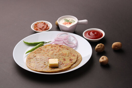 Traditional Indian food Aloo paratha or potato stuffed flat bread. served with pickle  tomato ketchup and curd, butter, onion, chili.