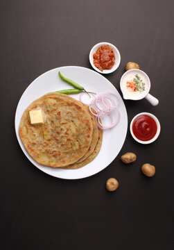 Traditional Indian food Aloo paratha or potato stuffed flat bread. served with pickle  tomato ketchup and curd, butter, onion, chili.