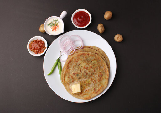 Traditional Indian food Aloo paratha or potato stuffed flat bread. served with pickle  tomato ketchup and curd, butter, onion, chili.