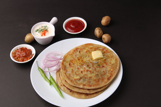 Traditional Indian food Aloo paratha or potato stuffed flat bread. served with pickle  tomato ketchup and curd, butter, onion, chili.