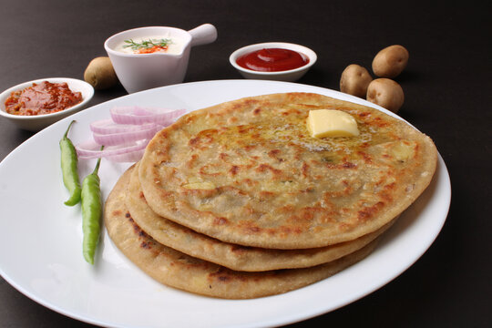 Traditional Indian food Aloo paratha or potato stuffed flat bread. served with pickle  tomato ketchup and curd, butter, onion, chili.