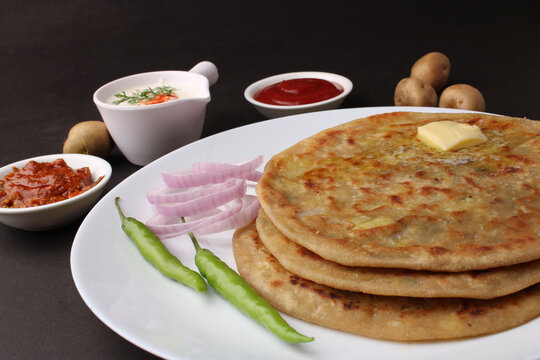 Traditional Indian food Aloo paratha or potato stuffed flat bread. served with pickle  tomato ketchup and curd, butter, onion, chili.
