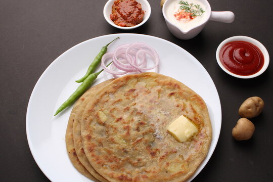 Traditional Indian food Aloo paratha or potato stuffed flat bread. served with pickle  tomato ketchup and curd, butter, onion, chili.
