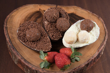 Chocolate Easter Eggs filled with brigadeiro (brigadier), powdered milk and strawberries. Goumert egg chocolate tradition in Brazil. Wood Background