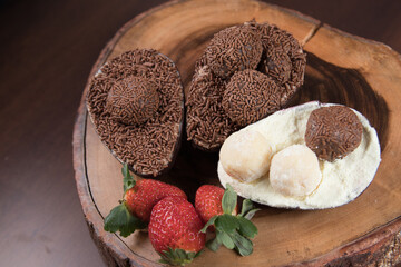 Chocolate Easter Eggs filled with brigadeiro (brigadier), powdered milk and strawberries. Goumert egg chocolate tradition in Brazil. Wood Background