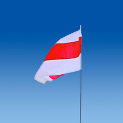 Isolated waving Belarusian national flag on blue sky background. White-red-white flag. A symbol of peaceful protests in Belarus against the dictatorship after presidential elections.