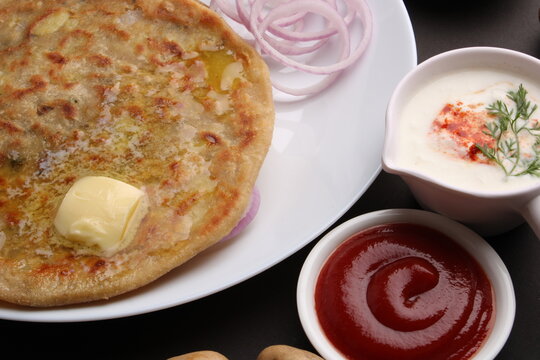 Traditional Indian food Aloo paratha or potato stuffed flat bread. served with pickle  tomato ketchup and curd, butter, onion, chili.