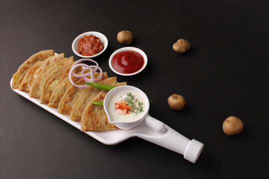 Traditional Indian food Aloo paratha or potato stuffed flat bread. served with pickle  tomato ketchup and curd, butter, onion chili.