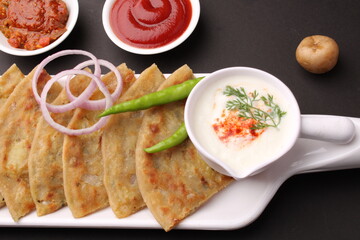 Traditional Indian food Aloo paratha or potato stuffed flat bread. served with pickle  tomato ketchup and curd, butter, onion chili.