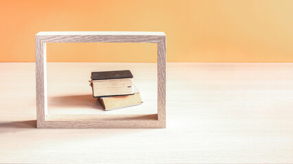 Books in a wooden photo frame on a wooden table