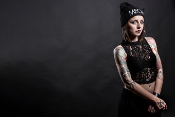 donna con cuffietka nera e  tatuaggi posa seria , isolata su sfondo nero