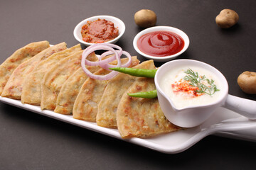 Traditional Indian food Aloo paratha or potato stuffed flat bread. served with pickle  tomato ketchup and curd, butter, onion chili.