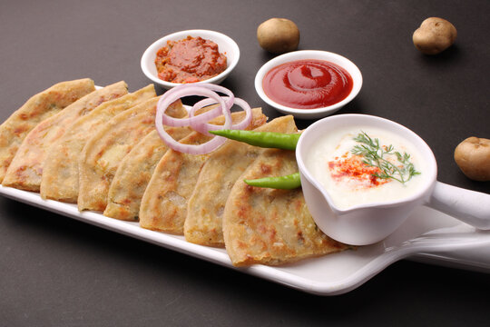 Traditional Indian food Aloo paratha or potato stuffed flat bread. served with pickle  tomato ketchup and curd, butter, onion chili.