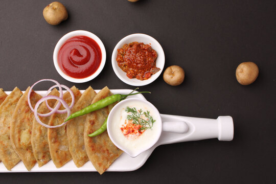 Traditional Indian food Aloo paratha or potato stuffed flat bread. served with pickle  tomato ketchup and curd, butter, onion chili.