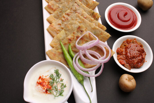 Traditional Indian food Aloo paratha or potato stuffed flat bread. served with pickle  tomato ketchup and curd, butter, onion chili.