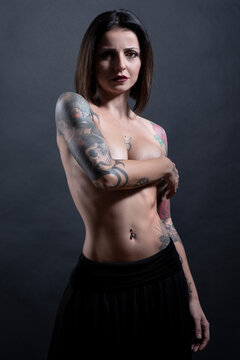 bellissima ragazza  mora con i tatuaggi mostra il corpo nudo, isolata su sfondo neutro 