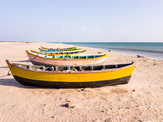 Naklejka na ściany i meble Colorful wooden fishing boats idling on a quiet white sand beach in the island of Dhanushkodi near the town of Rameshwaram.
