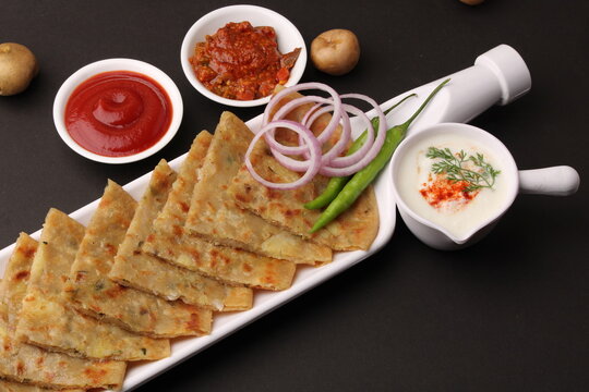 Traditional Indian food Aloo paratha or potato stuffed flat bread. served with pickle  tomato ketchup and curd, butter, onion chili.