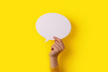 Dialogue icon, blank speech bubble in hand over yellow bacckground, layout image