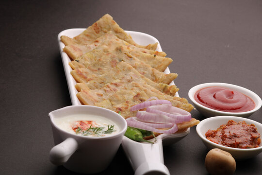 Traditional Indian food Aloo paratha or potato stuffed flat bread. served with pickle  tomato ketchup and curd, butter, onion chili.