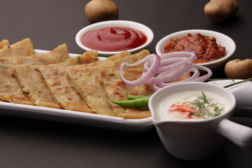 Traditional Indian food Aloo paratha or potato stuffed flat bread. served with pickle  tomato ketchup and curd, butter, onion chili.