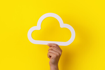 Cloud computing concept, hand holding cloud over yellow background, cloud storage