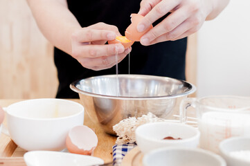 Man in the kitchen cooking a dough. Hands breaks an egg into a bowl ,hands pouring bitten egg ,Baking concept
