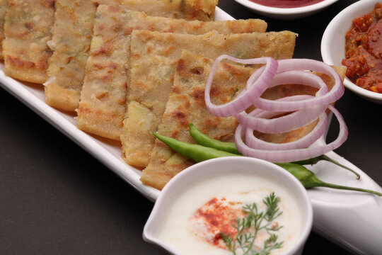 Traditional Indian food Aloo paratha or potato stuffed flat bread. served with pickle  tomato ketchup and curd, butter, onion chili.