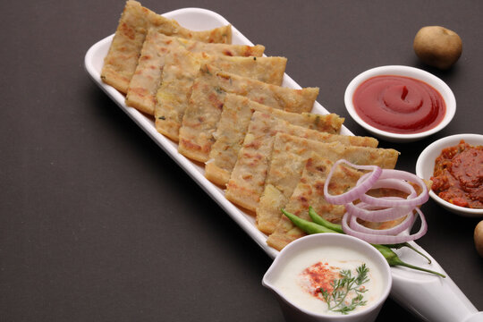 Traditional Indian food Aloo paratha or potato stuffed flat bread. served with pickle  tomato ketchup and curd, butter, onion chili.
