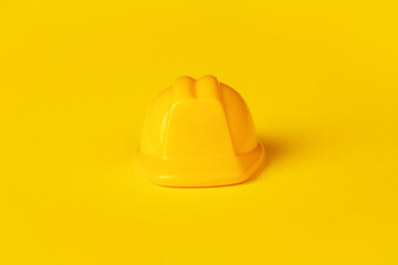 Yellow plastic hardhat over yellow background
