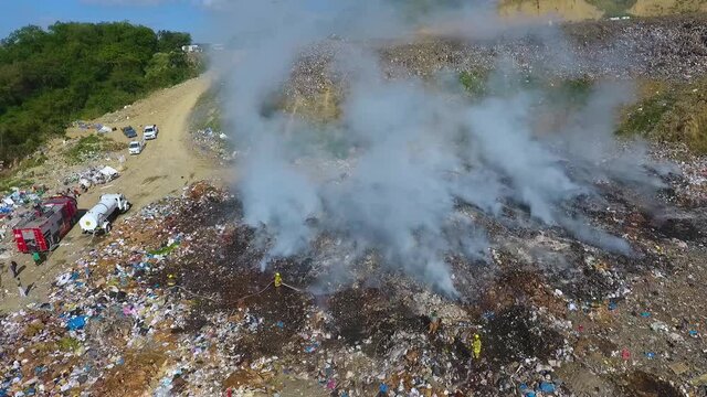 Firefighters using hoses, to extinguish a junkyard fire - aerial drone view