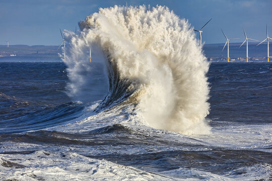 A Huge Fan Shaped Wave with Wind Turbines in the distance. Hartlepool, England, UK.