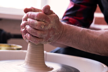 Potter wheel and hands of craftsman making a jug