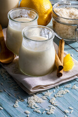 Appetizing rice pudding in glass jars with cinnamon sticks, grains of rice, milk and lemons. Ready to eat!. Homemade look.