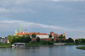 Wawel Royal Castle in Krakow, Poland. Exterior view from the Vistula River. Barges with restaurants standing by the river bank.