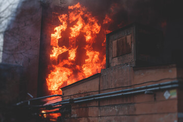 Massive large blaze fire in the city, brick factory building on fire, hell major fire explosion flame blast,  with firefighters team firemen on duty, arson, burning house damage destruction