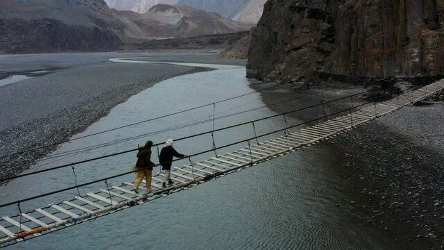 Pakistani Women Crossing The Hussaini Suspension Bridge Above Hunza River In Hunza, Gilgit-Baltistan, Pakistan. - Aerial Shot