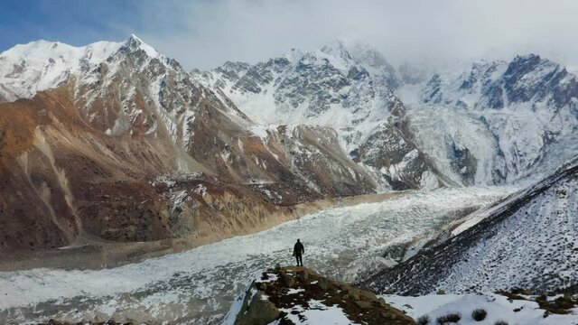 Man Standing On Top Of The Cliff Overlooking The Raikot Glacier And Nanga Parbat In Gilgit-Baltistan, Pakistan - aerial panoramic shot