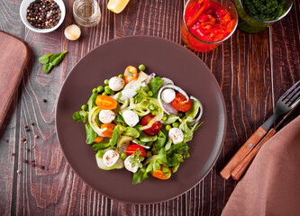 salad of fresh cherry tomatoes, mozzarella, basil, radish and other greens on the dinner table