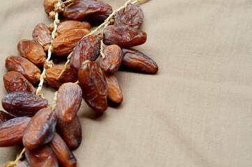 Dates (Phoenix dactylifera) on a wooden bowl on a brown cloth background. food for breaking the fast during Ramadan for Muslims. selective focus
