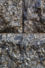 Beautiful rough texture of black granite in symmetrically stacked blocks.