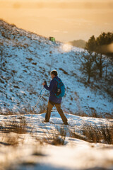 Male hiking on a snowy hill during sunset